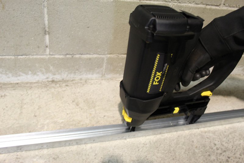FOX Gas nailer in action mounting a metal bar to a wall